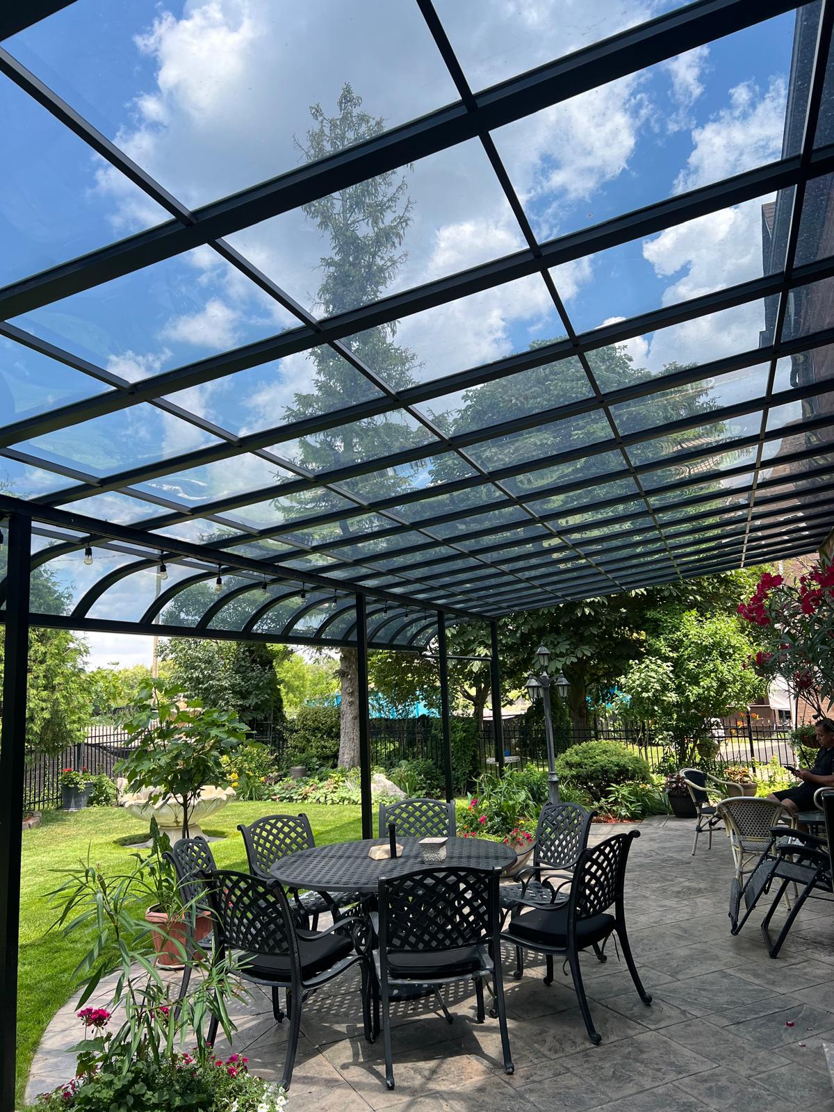 Curved glass patio cover over a backyard dining area